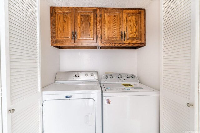 clothes washing area featuring separate washer and dryer and cabinet space