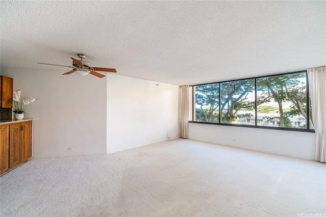 unfurnished living room with a textured ceiling, carpet floors, and a ceiling fan