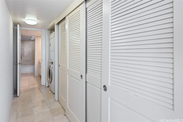 corridor featuring stacked washer / dryer and light tile patterned floors