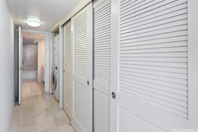 hall featuring stacked washing maching and dryer and light tile patterned floors