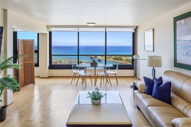 living room with expansive windows, a water view, and light wood-type flooring