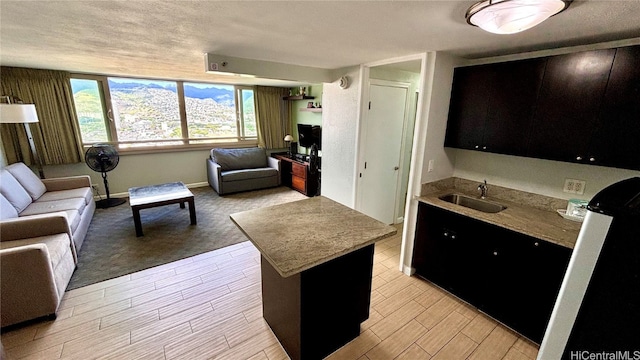 kitchen featuring sink, a center island, a textured ceiling, and light wood-type flooring