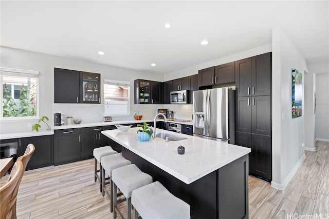 kitchen featuring stainless steel appliances, a kitchen bar, sink, and an island with sink