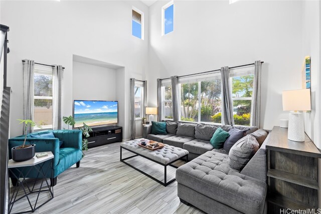 living room featuring a wealth of natural light, light hardwood / wood-style flooring, and a towering ceiling