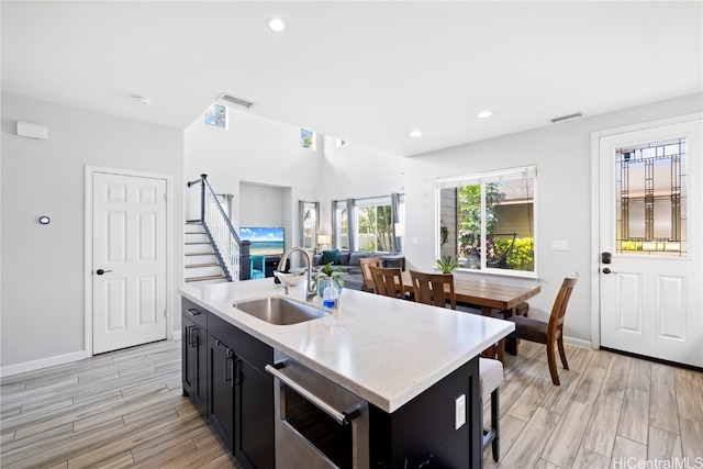 kitchen with sink, an island with sink, dishwasher, and light hardwood / wood-style floors