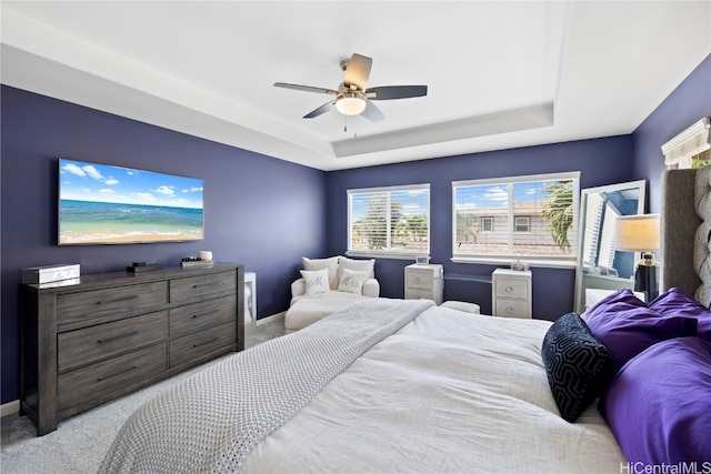 bedroom with a raised ceiling, light carpet, and ceiling fan