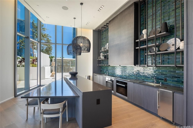 kitchen with dark countertops, wall oven, backsplash, modern cabinets, and floor to ceiling windows