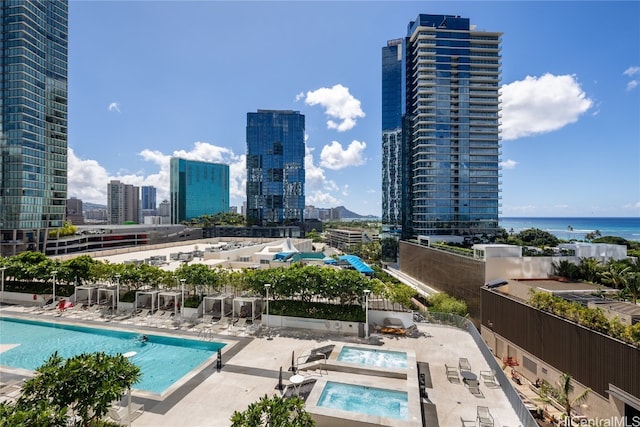 view of pool featuring a hot tub, a patio, and a water view