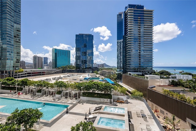 community pool with a hot tub, a patio, and a view of city