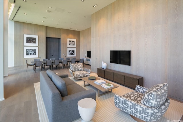 living room featuring wood finished floors, a towering ceiling, recessed lighting, and baseboards