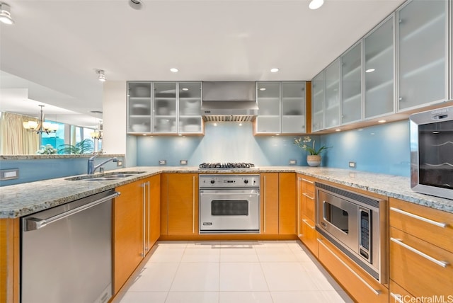 kitchen with light stone counters, sink, extractor fan, and appliances with stainless steel finishes