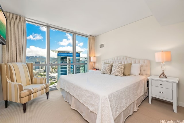 bedroom featuring a wall of windows, a mountain view, and light carpet