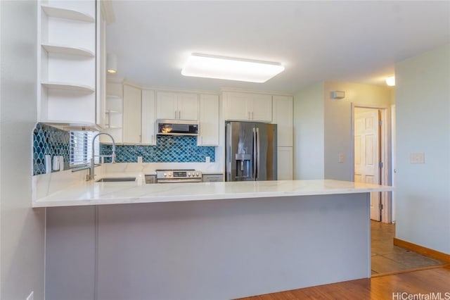 kitchen with stainless steel appliances, a sink, a peninsula, and open shelves