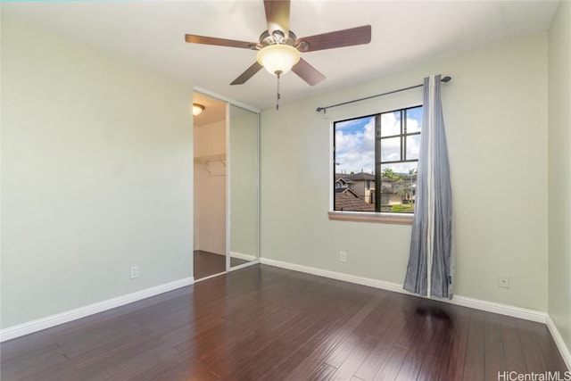 unfurnished bedroom featuring dark wood-style floors, a closet, and baseboards