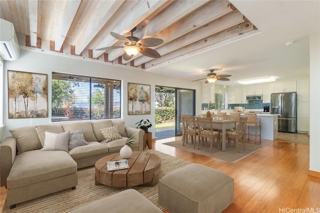 living room featuring a wall mounted air conditioner, beam ceiling, light hardwood / wood-style flooring, and ceiling fan