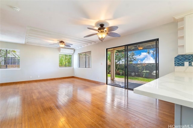 unfurnished living room featuring light wood finished floors, baseboards, and a ceiling fan