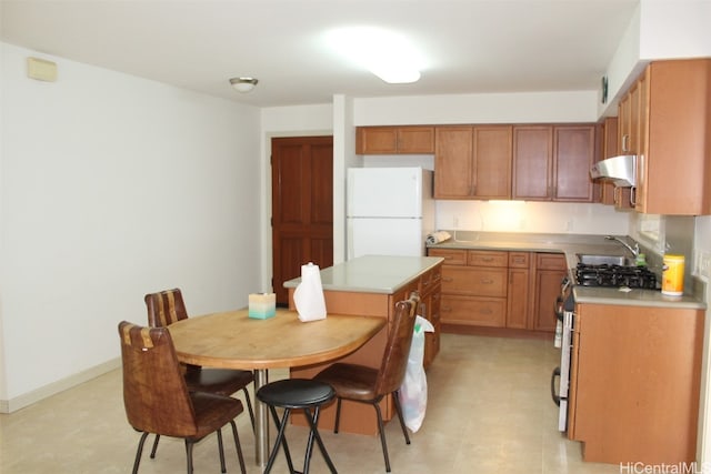 kitchen featuring stainless steel gas stove, sink, white refrigerator, and a kitchen island