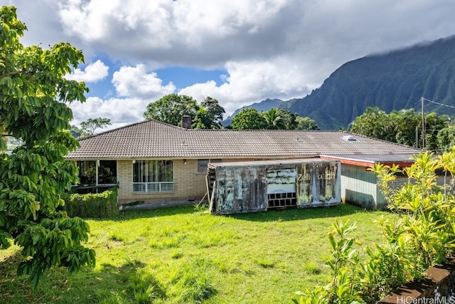 rear view of house with a yard and a mountain view