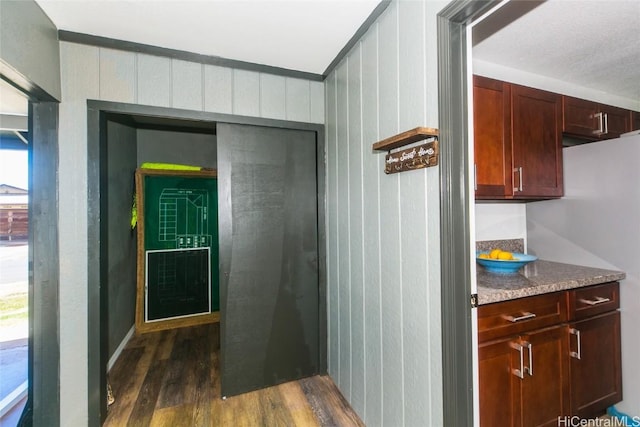 corridor with dark wood-type flooring and wooden walls