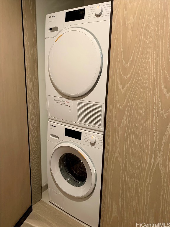 laundry area featuring light hardwood / wood-style floors and stacked washer and clothes dryer