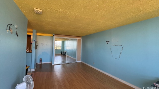 spare room with a textured ceiling and dark hardwood / wood-style flooring