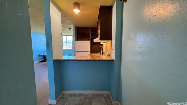 kitchen featuring light hardwood / wood-style flooring, a textured ceiling, white fridge, and sink