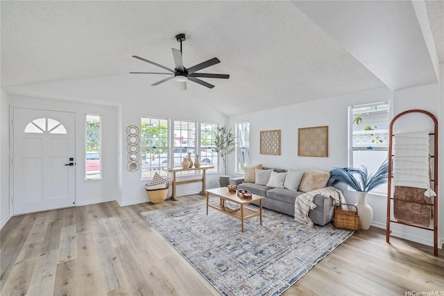 living area with ceiling fan, a wealth of natural light, and light wood-style floors