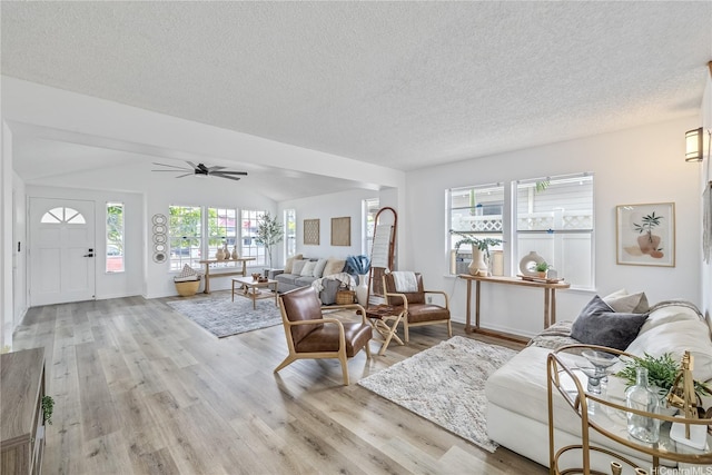 living room with a textured ceiling, light wood-style floors, ceiling fan, baseboards, and lofted ceiling