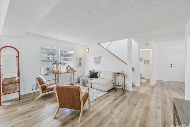 living room with light hardwood / wood-style flooring, cooling unit, and a textured ceiling