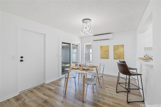 dining room featuring a textured ceiling, light hardwood / wood-style floors, an AC wall unit, and an inviting chandelier