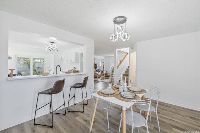 dining room with stairs, wood finished floors, a textured ceiling, and a chandelier