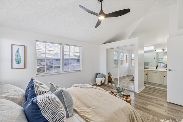 bedroom featuring ensuite bathroom, vaulted ceiling, ceiling fan, light hardwood / wood-style flooring, and a closet