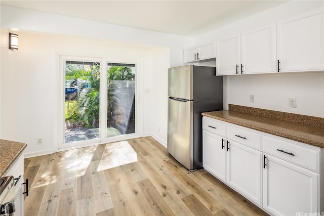 91-1019 Hiluhilu St, Kapolei, HI 96707 - kitchen with freestanding refrigerator, white cabinets, light wood finished floors, and dark stone countertops