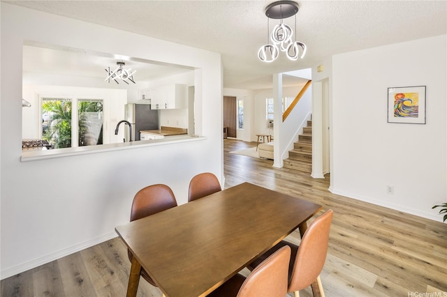 91-1019 Hiluhilu St, Kapolei, HI 96707 - dining area with a chandelier, light wood-type flooring, stairway, baseboards, and a textured ceiling