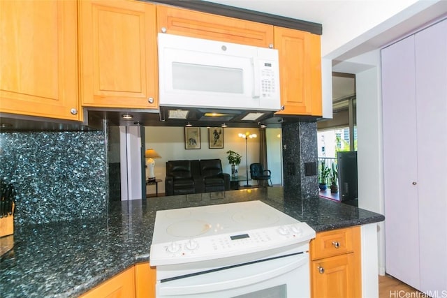 kitchen featuring backsplash, dark stone counters, and white appliances