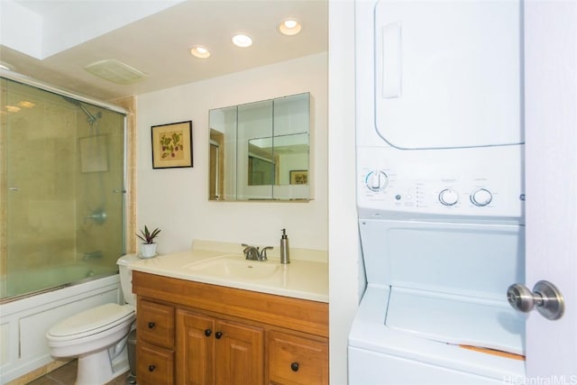 full bathroom featuring toilet, combined bath / shower with glass door, tile patterned floors, vanity, and stacked washing maching and dryer