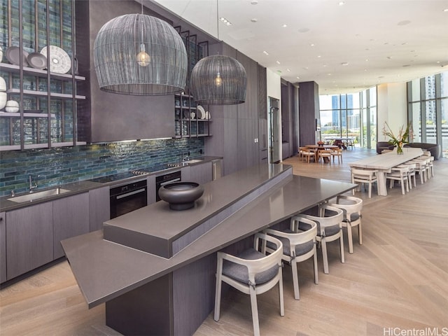 kitchen featuring decorative backsplash, oven, sink, decorative light fixtures, and floor to ceiling windows