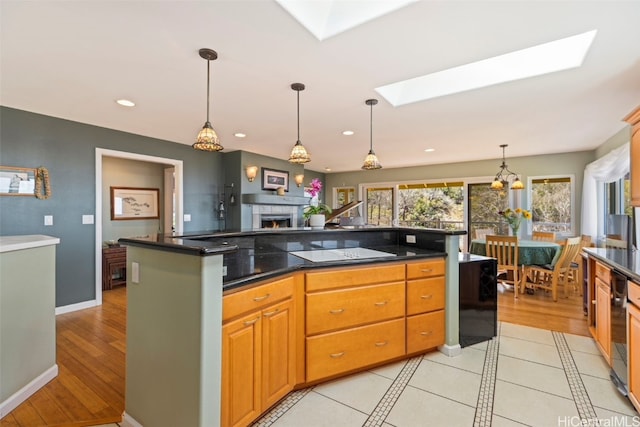 kitchen with black electric stovetop, light wood-type flooring, hanging light fixtures, and a skylight