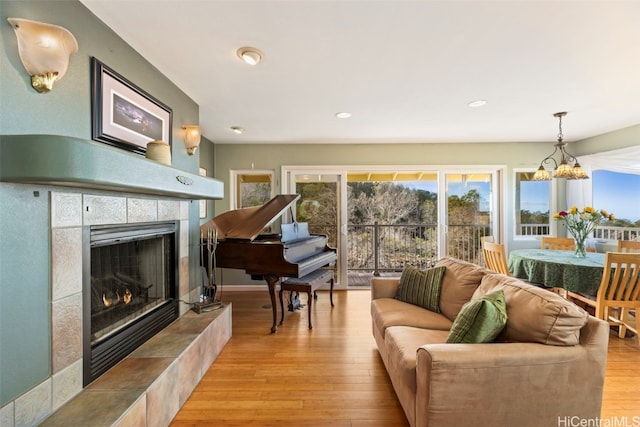 sitting room featuring a tiled fireplace, an inviting chandelier, and light wood-type flooring