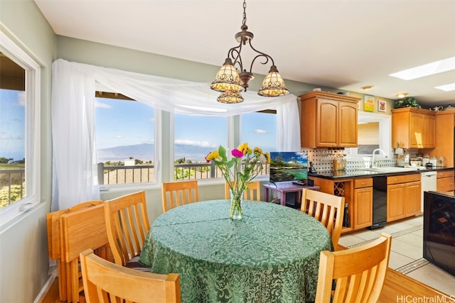 kitchen featuring a skylight, sink, tasteful backsplash, pendant lighting, and light hardwood / wood-style floors