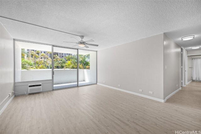 spare room with a healthy amount of sunlight, an AC wall unit, and light hardwood / wood-style floors