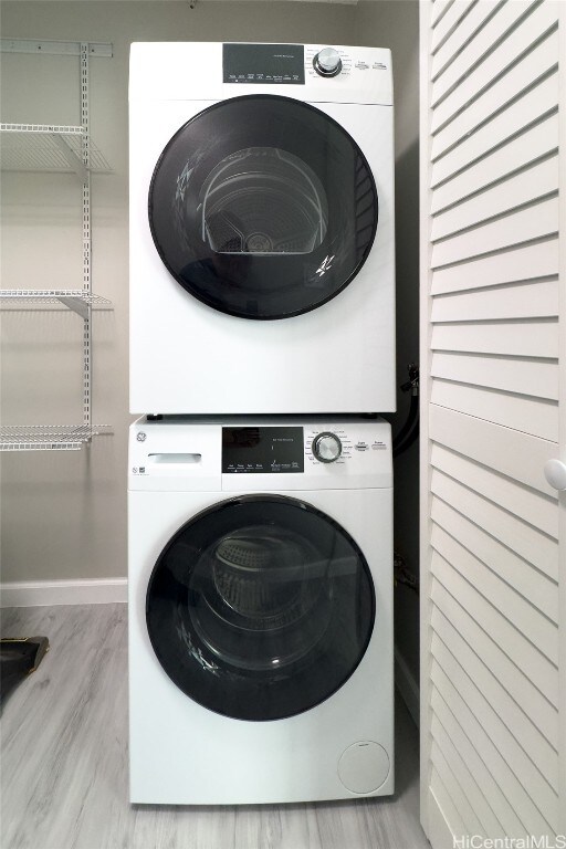 laundry room with stacked washer / dryer and light hardwood / wood-style floors