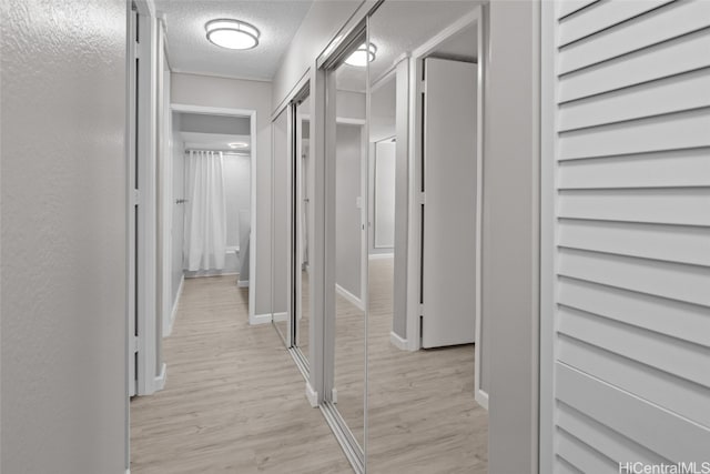 corridor featuring light hardwood / wood-style floors and a textured ceiling