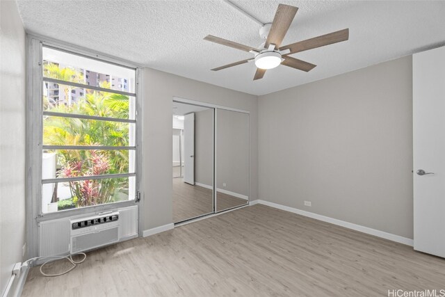 unfurnished bedroom featuring a closet, ceiling fan, a textured ceiling, and light wood-type flooring