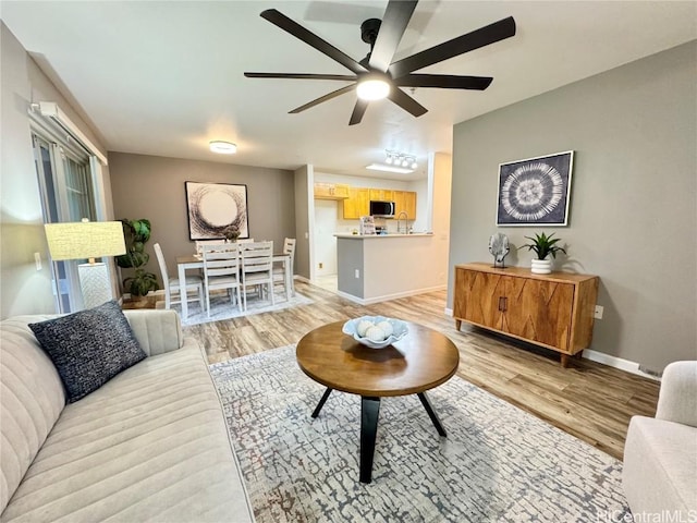 living room with ceiling fan and light hardwood / wood-style flooring