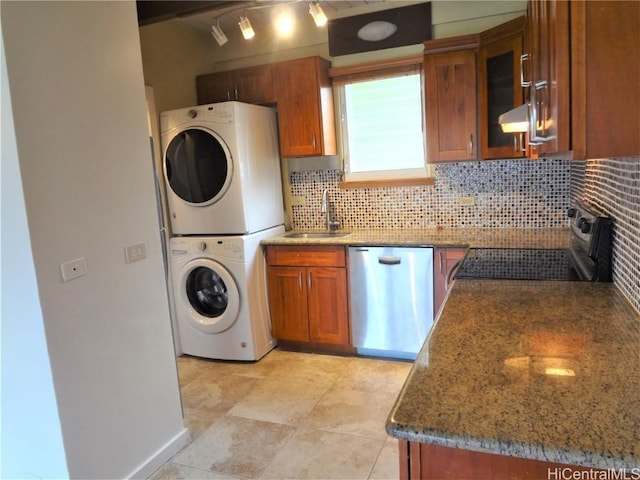 kitchen featuring sink, dishwasher, range, stacked washer / drying machine, and decorative backsplash