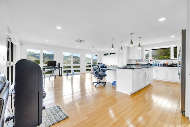 kitchen featuring a center island, pendant lighting, light hardwood / wood-style floors, and white cabinets