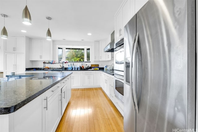 kitchen with white cabinets, light wood-type flooring, stainless steel appliances, decorative light fixtures, and a center island