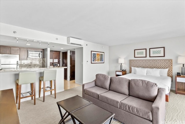 bedroom featuring light colored carpet, stainless steel fridge, an AC wall unit, and rail lighting