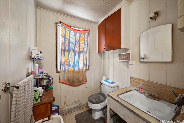 bathroom with vanity, wooden walls, toilet, and tile patterned flooring